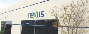 A Nexus manufacturing representative standing in front of a building with a sign that says Nexus-Now.